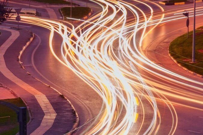 A vibrant long exposure photo capturing light trails at an urban intersection during nighttime.